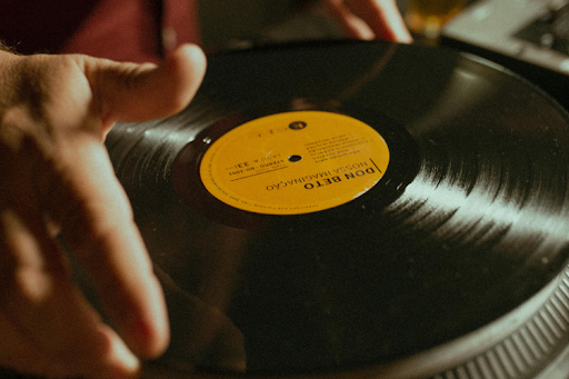 Hand holding a vinyl record by the edges to avoid touching the grooves.