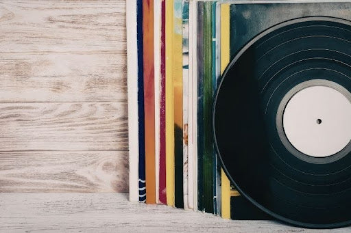 Vinyl record collection stacked on wooden surface.